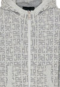 Felpa con cappuccio e zip in maglia grigia chiara, caratterizzata da un motivo geometrico ripetuto, zip frontale e tasche laterali. Texture morbida.