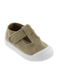 Zapatilla de lona color beige con una correa de Velcro, puntera redonda y suela de goma blanca con textura estriada. Diseñada para la comodidad y la facilidad de uso.