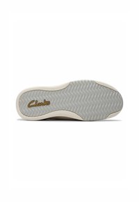 Clarksin kengän pohja, jossa on teksturoitu harmaa kumimateriaali, aaltoilevalla kuviolla ja vaaleanbeige reunus. "Clarks"-logo on kultainen.
