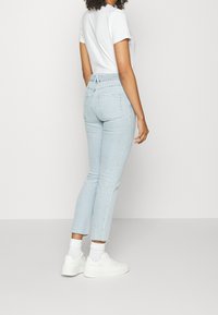 Ljusblå, högmidjade jeans med smal passform, försedda med bakfickor och fransad fåll. Kombineras med vita sneakers och ankelsockor.