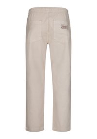 Beige bomullbyxor med elastisk midja, två bakfickor och en liten logotypflik på höger ficka. Skräddarsydd rakt ben-design.