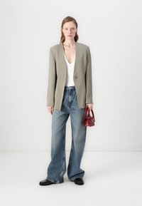 Overdimensjonert grå blazer med en enkelt knapp, hvit V-hals topp, brede blå jeans og en liten rød håndveske med strukturert design.