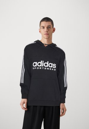 Sudadera negra con bolsillo frontal, que presenta el texto blanco "adidas SPORTSWEAR". Tres rayas blancas en cada manga. Tela suave y corte relajado.