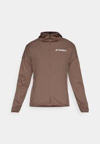 Giacca marrone con zip sul davanti, maniche lunghe e cappuccio. Presenta una texture liscia e il logo "TERREX" in bianco sul petto.