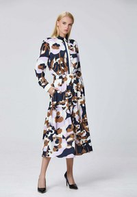 Robe à manches longues présentant un motif abstrait multicolore en bleu marine, marron et lavande ; taille élastique, jupe à volants et poches.