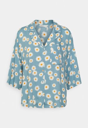 Camisa azul de manga corta con botones, con estampado floral de margaritas blancas y amarillas y un pequeño bolsillo en el pecho.