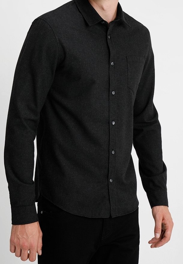 Zwart overhemd met lange mouwen, gemaakt van gestructureerde stof, voorzien van een borstzak en een standaardkraag, gecombineerd met een donkere broek.