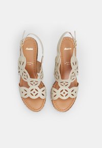 Bežid slingback sandaalid lõikega lillemustriga, pruun sisetald, tan värvi õmblused ja kuldne pandla detail. Siledast materjalist ja lamedal tallal.