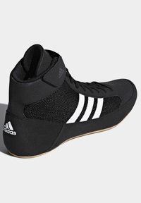 Black high-top athletic shoe with mesh panels, white three-stripe design, rubber sole, and padded collar for support.