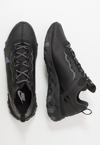 Svarta träningsskor med en strukturerad mesh-övre, grå accenter, snörningsdesign och en dämpad, robust gummisula för grepp.