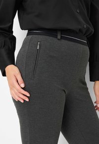 Pantaloni grigi scuri con una superficie liscia, dotati di una tasca laterale con zip e una cintura elegante con una sottile striscia di accento.