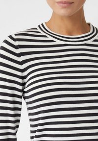 Maglione a righe bianche e nere con un colletto rotondo a coste e una texture morbida, caratterizzato da righe orizzontali alternate di larghezza uniforme.