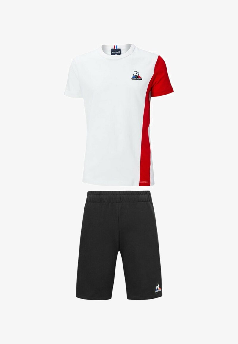 Camiseta blanca con panel lateral rojo, logo en el pecho; pantalones cortos atléticos negros con cintura elástica y logo. Material de mezcla de algodón.