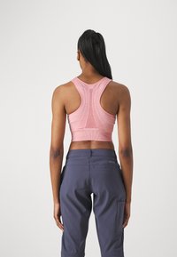 Top corto sin mangas rosa con un respaldo texturizado y panel de malla, combinado con pantalones azul oscuro que tienen un bolsillo lateral y una tela suave.