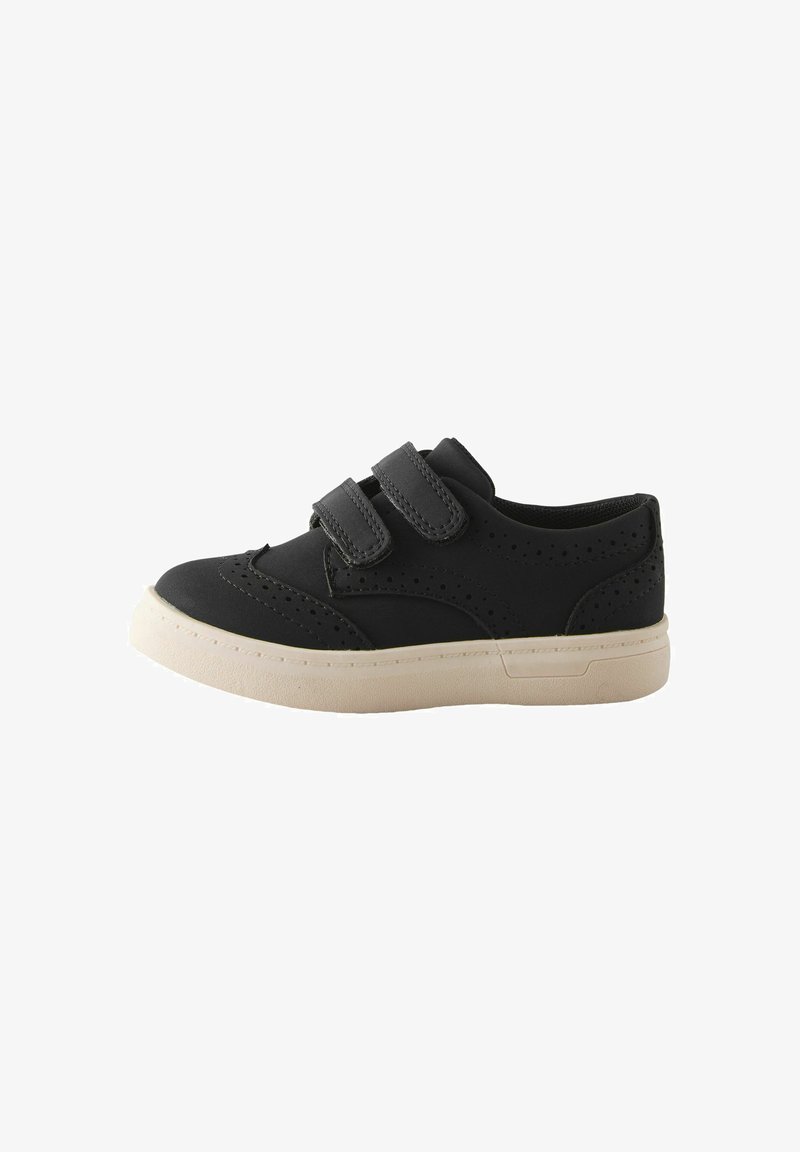 Chaussure décontractée noire avec semelle blanche, deux brides velcro et perforations décoratives sur les côtés et la zone des orteils.