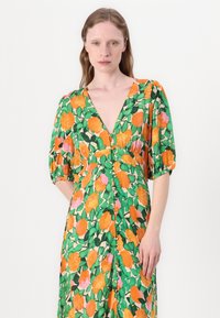Grünes Blumenkleid mit orangefarbenen und rosa-Rosen, V-Ausschnitt, Puffärmeln und durchgehender Knopfleiste. Leichter Stoff mit lebhaften Farben.