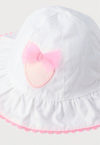 Λευκό παιδικό καπέλο ηλίου με βολάν στο γείσο, ροζ κυματιστό περίγραμμα και ροζ μπαλώμα φράουλας με ροζ δίχτυνο φιόγκο.