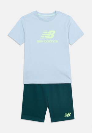 Ανοιχτό μπλε κοντομάνικο πουκάμισο New Balance με κίτρινο λογότυπο και σκούρο πράσινο σορτς με μικρό κίτρινο λογότυπο New Balance.