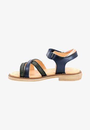Sandalias sintéticas de color azul marino con correas entrelazadas, que presentan un detalle texturizado en verde. Suela plana con plantilla en color beige y correa ajustable en el tobillo.