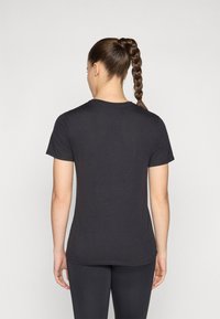 T-shirt noir à manches courtes en tissu doux, avec un col rond et une coupe ajustée, présentant une texture lisse et sans motifs visibles.