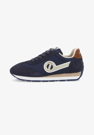 Navy blue sneakers with a suede texture, white logo accent, beige rubber sole, and brown heel detail. Features traditional lace-up design.
