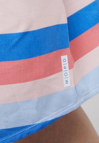 Tissu rayé en rose, bleu et bleu clair, avec une étiquette de marque visible "MOPID" sur l'ourlet. Texture lisse, design décontracté.