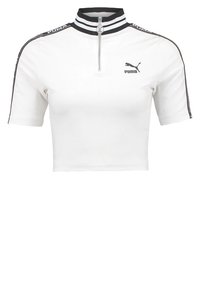 Bílá zkrácená tričko Puma s černým pruhovaným límcem, předním zipem a logem na hrudi a podél ramenních pruhů.