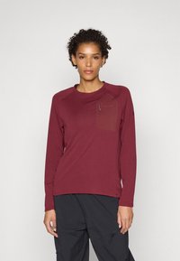 Haut marron à manches longues en tissu texturé, doté d'une poche poitrine et de manches raglan, associé à un pantalon cargo noir.