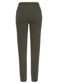 Olivgrüne Jogginghose mit elastischem Bund, Seitentaschen und schmal zulaufenden Beinen. Hergestellt aus weichem Stoff mit glatter Textur.