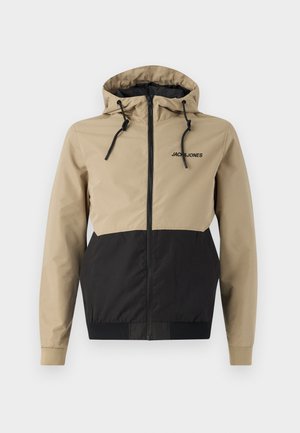 Hooded jacket featuring a beige upper and black lower panels, made of smooth material with drawstrings and a front zipper.
