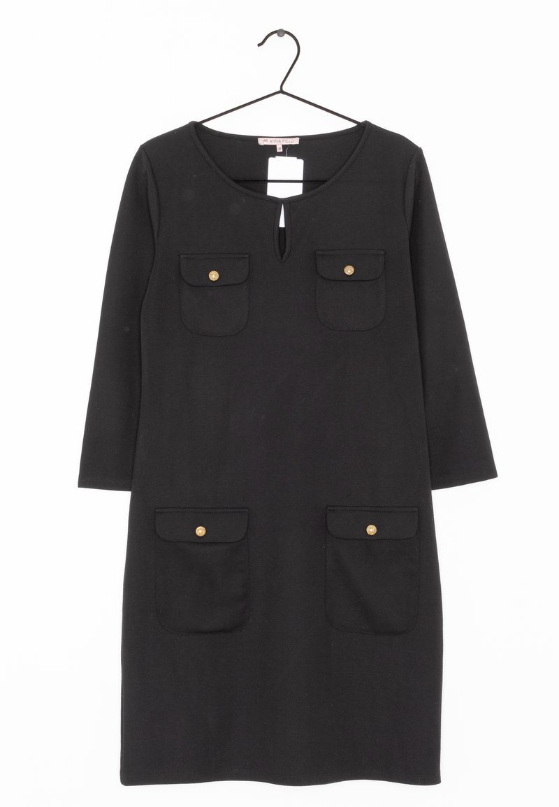 Robe noire longueur genou avec manches trois-quarts, quatre poches avant avec boutons dorés et un petit décolleté en forme de trou de serrure, suspendue sur un cintre noir.