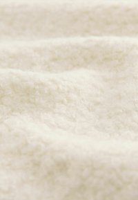 Tejido texturizado en color blanco roto con una superficie suave y esponjosa, que presenta un denso rizo y un brillo sutil. Ideal para aplicaciones acogedoras.