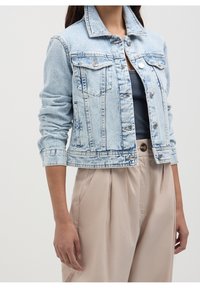 Light blue denim jacket with a classic collar, buttoned front, two chest pockets, and rolled-up sleeves; appears slightly distressed.