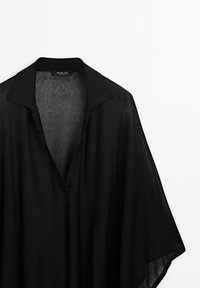 Black semi-sheer blouse with a wide collar and V-neck opening laid flat on a white background.