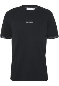 Zwarte katoenen T-shirt met ronde hals, korte mouwen en wit "CALVIN KLEIN" logo op de borst en mouwen met gebrandmerkte accenten.