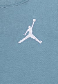Světle modré bavlněné tričko s bílou vyšitou logem Jumpman, umístěným centrálně, s hladkou texturou a designem s kulatým výstřihem.