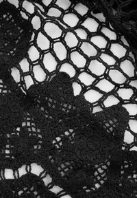 Czarna tkanina na szydełku z misternymi wzorami kwiatowymi i heksagonalnym wzorem siatkowym, o teksturowanym wykończeniu i różnorodnych detalach ściegów.