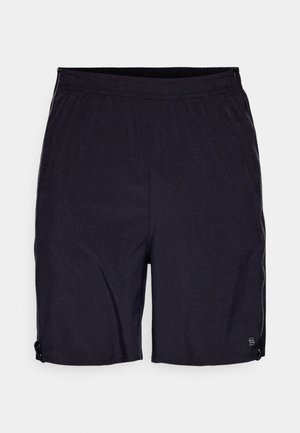 Fekete sportos rövidnadrág rugalmas anyagból, elasztikus derékkal, oldalsó cipzáras zsebekkel és egy kis logóval az alsó szegélyen.