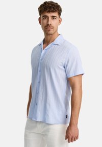 Lichtblauw shirt met korte mouwen, verticale strepen, knoopsluiting aan de voorkant en een klassieke kraag. De stof lijkt zacht en lichtgewicht te zijn.