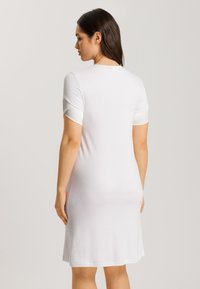Vestido blanco de manga corta, diseño ajustado, tela suave, hasta la rodilla, con acentos de manga en contraste y cuello redondo.
