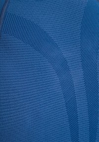 Tissu bleu avec différentes textures et motifs de tricot, comportant une fermeture éclair sur le côté supérieur gauche.