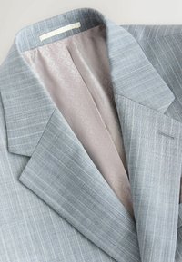 Blazer bleu clair avec un subtil motif rayé, doublure intérieure à motifs clairs contrastants et revers crantés.