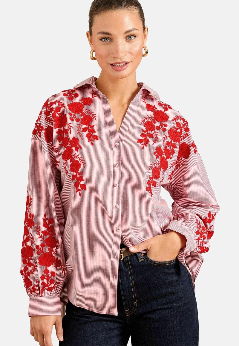 Camicia a righe rosse e bianche con ricami floreali sulle maniche, vestibilità morbida, colletto e maniche lunghe con polsini.