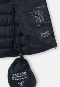 Chaleco acolchado negro ligero y fácil de empaquetar, hecho de un material a prueba de viento. Cuenta con cierre de cordón y un diagrama etiquetado de las características clave.