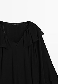 Schwarze Bluse mit V-Ausschnitt, aus weichem Stoff und fließenden Flügelärmeln. Das Design umfasst gefältelte Akzente am Halsauschnitt.