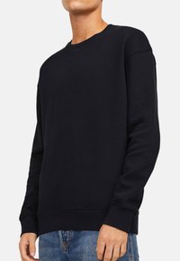 Felpa nera in misto cotone, con maniche lunghe, scollatura a girocollo e polsini e orlo a coste. Tessuto liscio, design semplice.