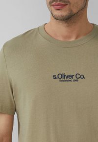 Olijfgroene T-shirt met korte mouwen van zachte katoen, met aan de voorkant een geborduurd blauw logo "s.Oliver Co. Established 1969."