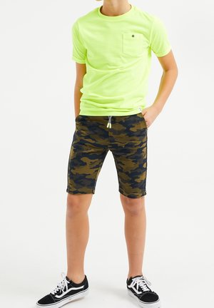 Neongelbes T-Shirt mit Brusttasche, kombiniert mit Camouflage-Shorts in Dunkelgrün und Schwarz, elastischem Bund und Kordelzug.