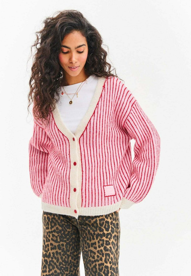 Růžový a bílý proužkovaný cardigan s texturou, výstřihem do V, červenými knoflíky a náprsní kapsou. Kombinován s kalhotami s leopardím potiskem.