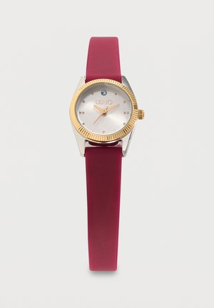 Montre femme avec lunette dorée, cadran blanc, un seul marqueur en cristal, aiguilles dorées et bracelet en silicone bordeaux.